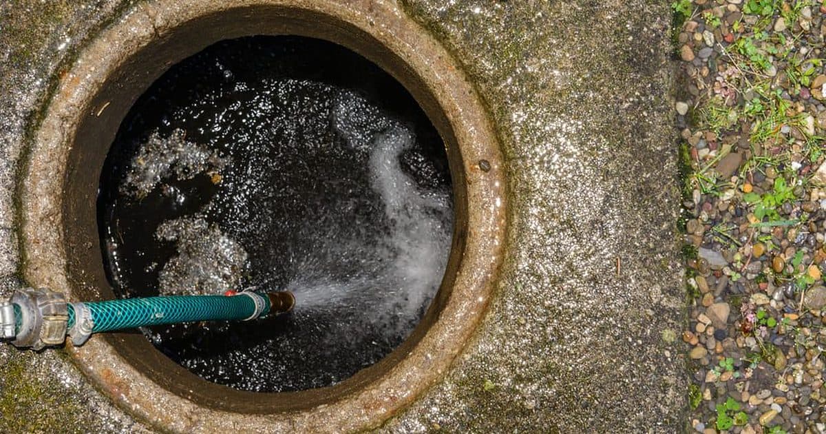Hogedrukreiniging van een rioolput met een spuitslang